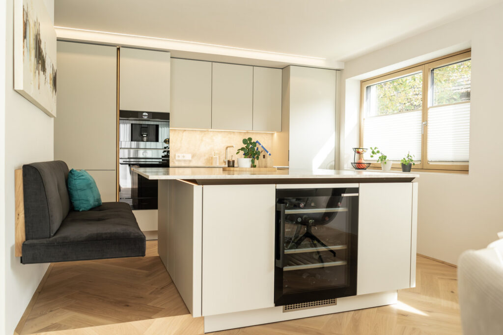 Helle Küche mit schwebender Sitzbank, Weinkühlschrank und Fischgrät-Parkett